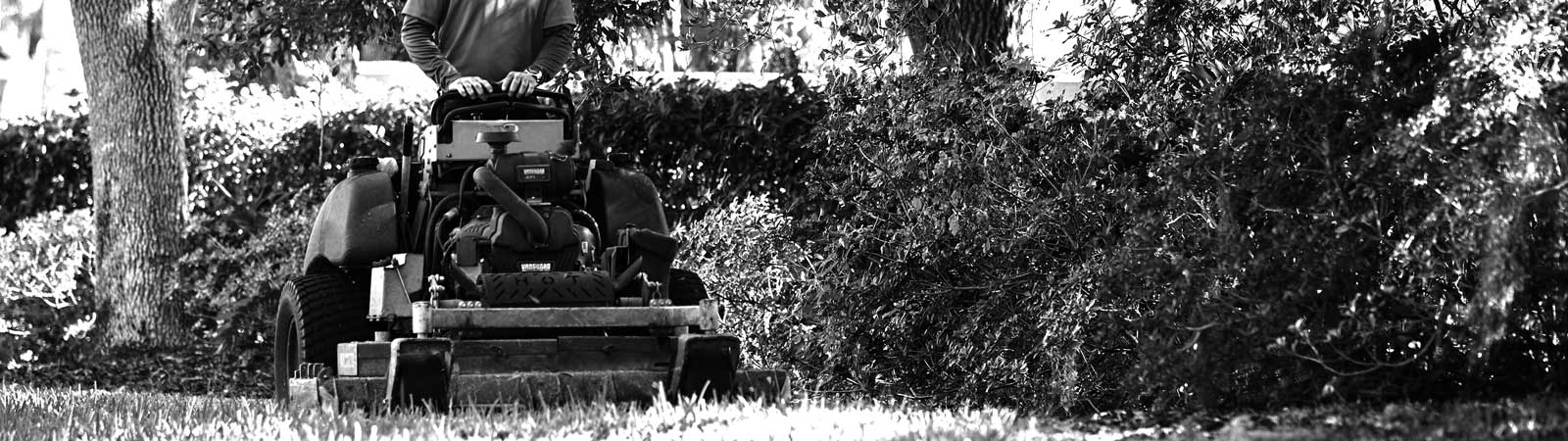 A person operating a zero-turn lawn mower powered by a Vanguard vertical shaft engine.