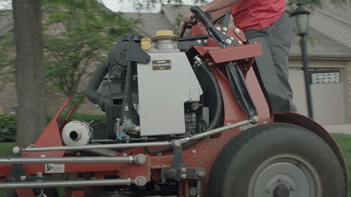 A person riding a zero-turn lawn mower powered by a Vanguard lawn mower engine.