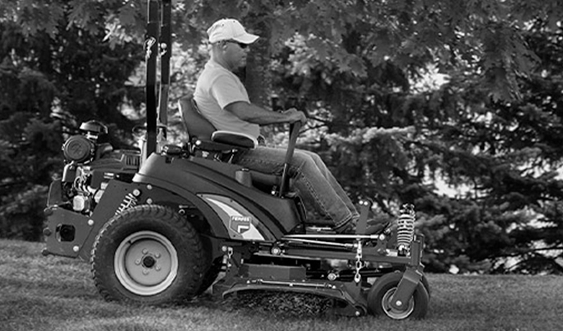 Man sitting on a zero-turn lawn mower powered by a Vanguard engine in the park.
